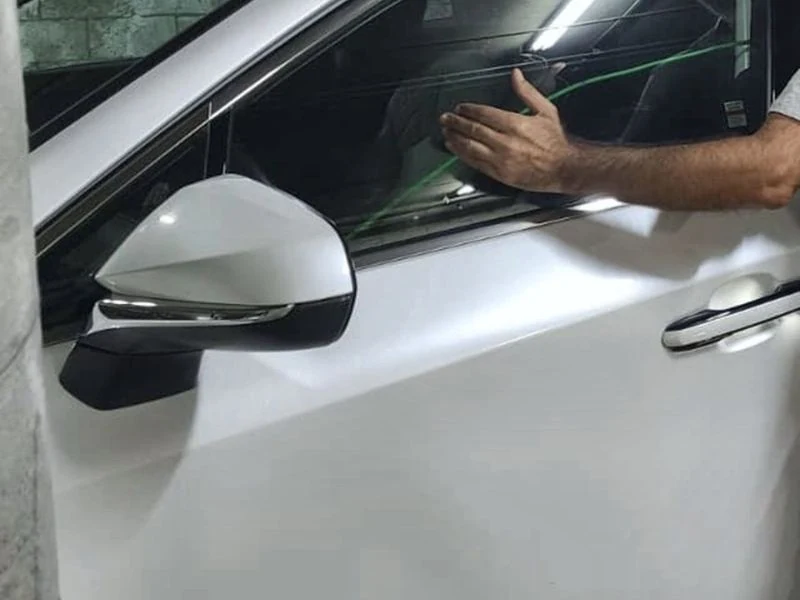 Technician unlocking a car door with a long-reach tool at the window