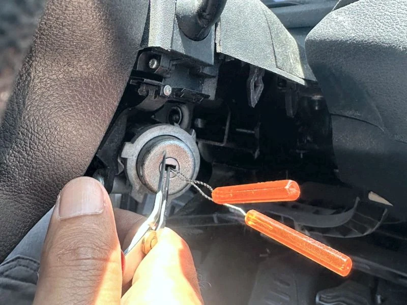 Locksmith working on a vehicle ignition lock with precision tools