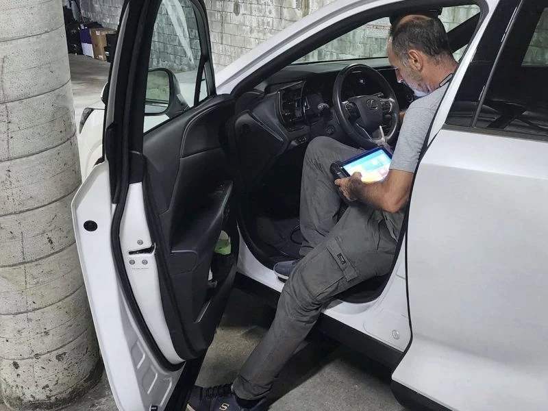 Technician in the driver’s seat programming a key with a diagnostic tablet