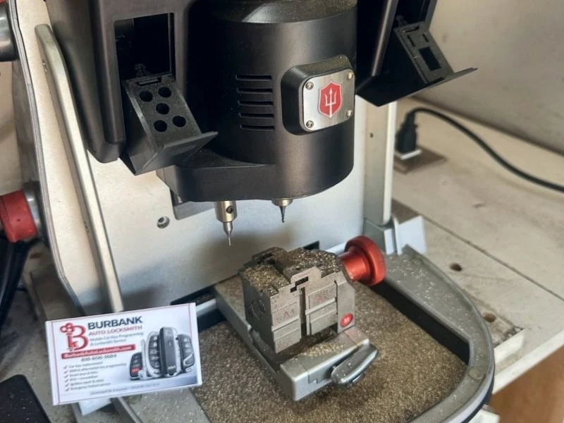 Key-cutting machine with a Burbank Auto Locksmith business card on the bench